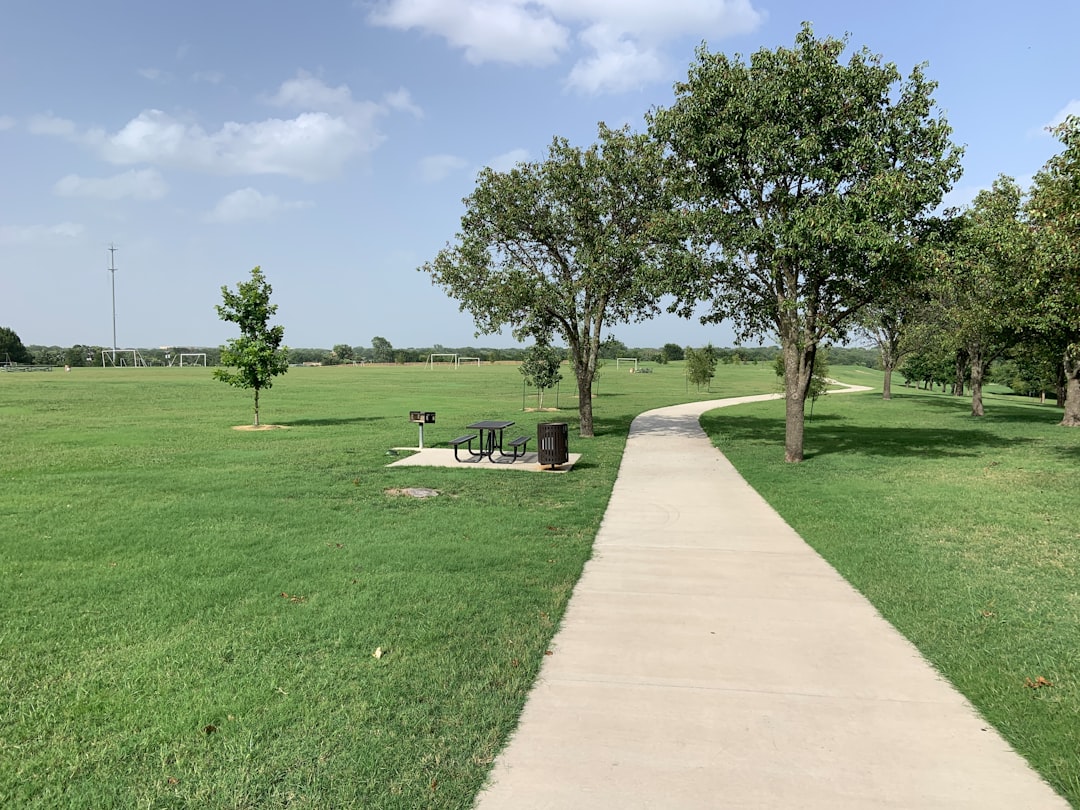 A green golf course fairway with trees under a warm Texas sky